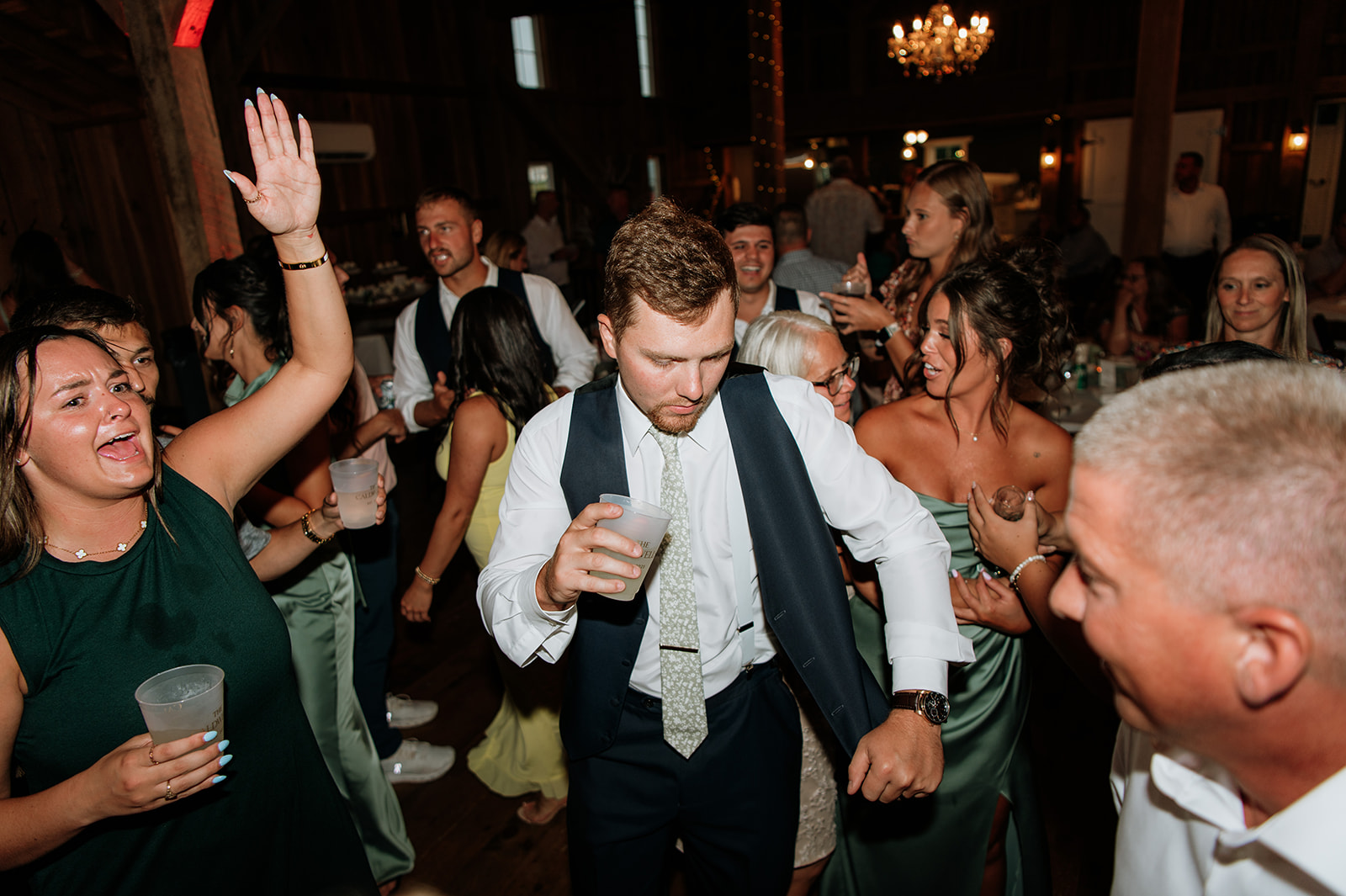 Groom dancing during his reception surrounded by guests