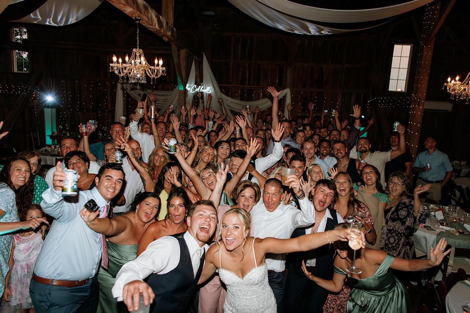 Wedding guests cheering and posing for group photo on the dance floor inside Rock Run Creek Barn.