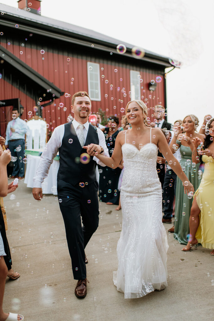 Bride and groom smiling as bubbles float around them during mock exit at Rock Run Creek Barn.