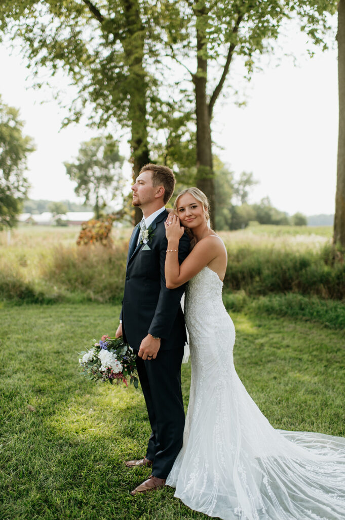 Bride hugging groom from behind during outdoor portraits at Rock Run Creek Barn wedding.