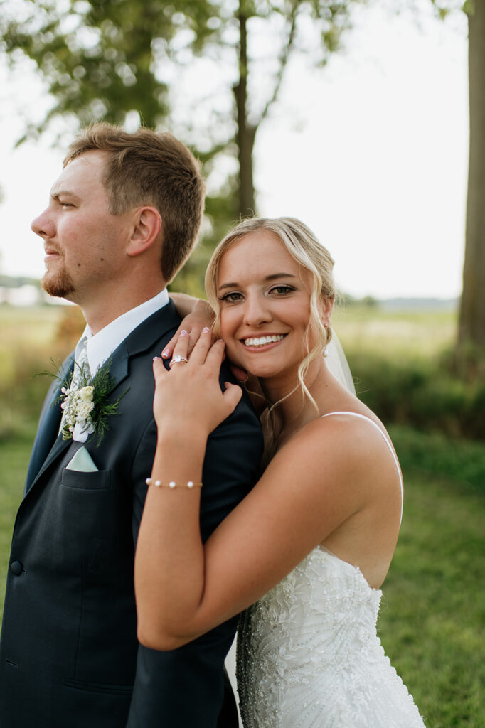 Bride hugging groom from behind during outdoor portraits at Rock Run Creek Barn wedding.