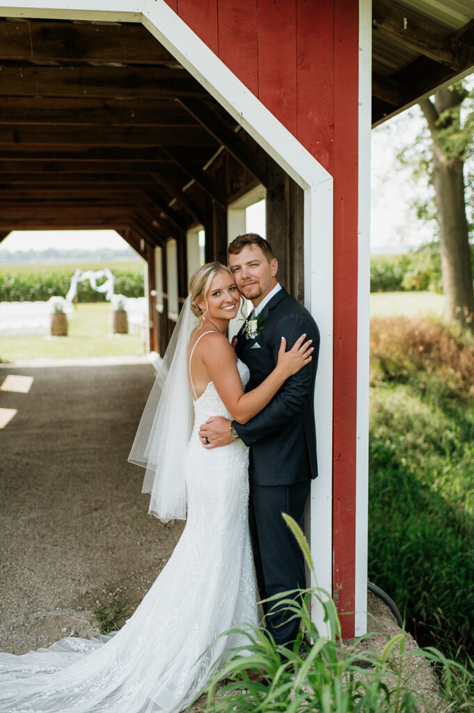 Couple smiling together under the red covered bridge at Rock Run Creek Barn wedding.