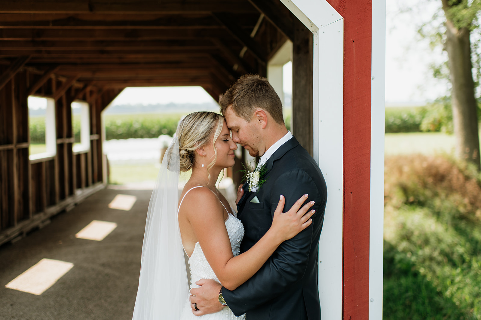 Bride and groom forehead to forehead in covered bridge at Rock Run Creek Barn.