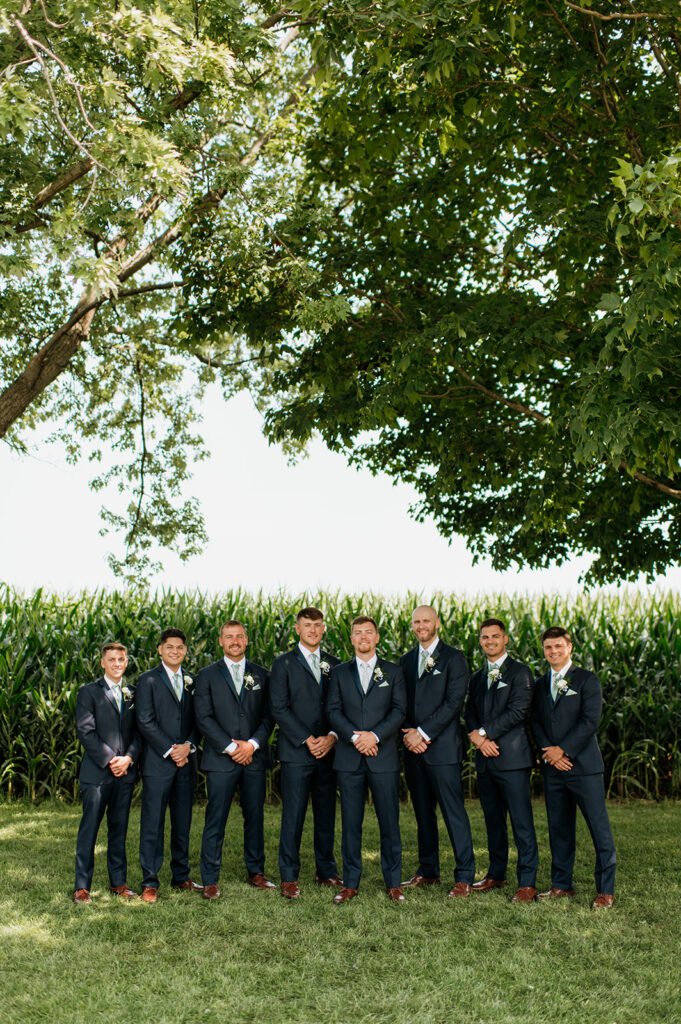Outdoor groom and groomsmen portrait in front of a cornfield at Rock Run Creek Barn in Goshen, Indiana