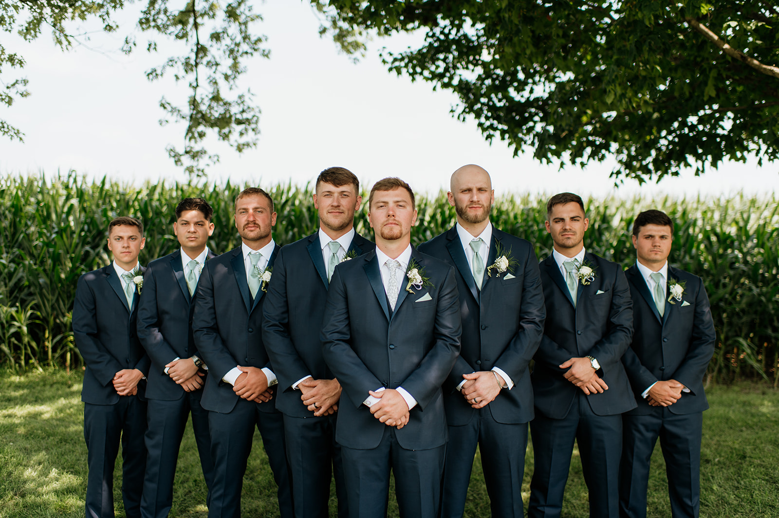 Outdoor groom and groomsmen portrait in front of a cornfield at Rock Run Creek Barn in Goshen, Indiana