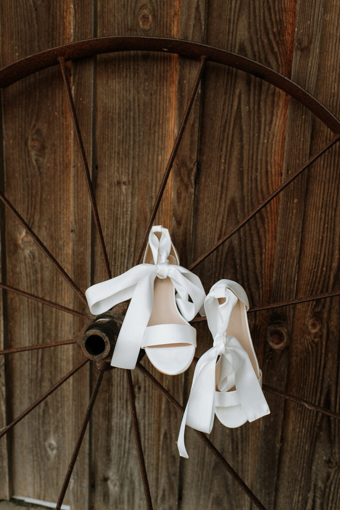 Wedding detail shot of the brides heels hanging off of a wheel