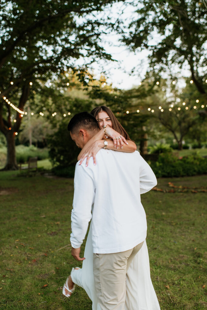 Close-up photo of couple hugging and laughing under the trees at Saint Mary’s College.