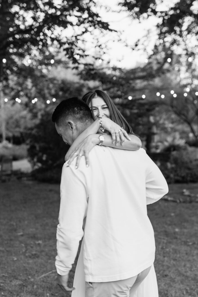 Close-up black and white photo of couple hugging and laughing under the trees at Saint Mary’s College.