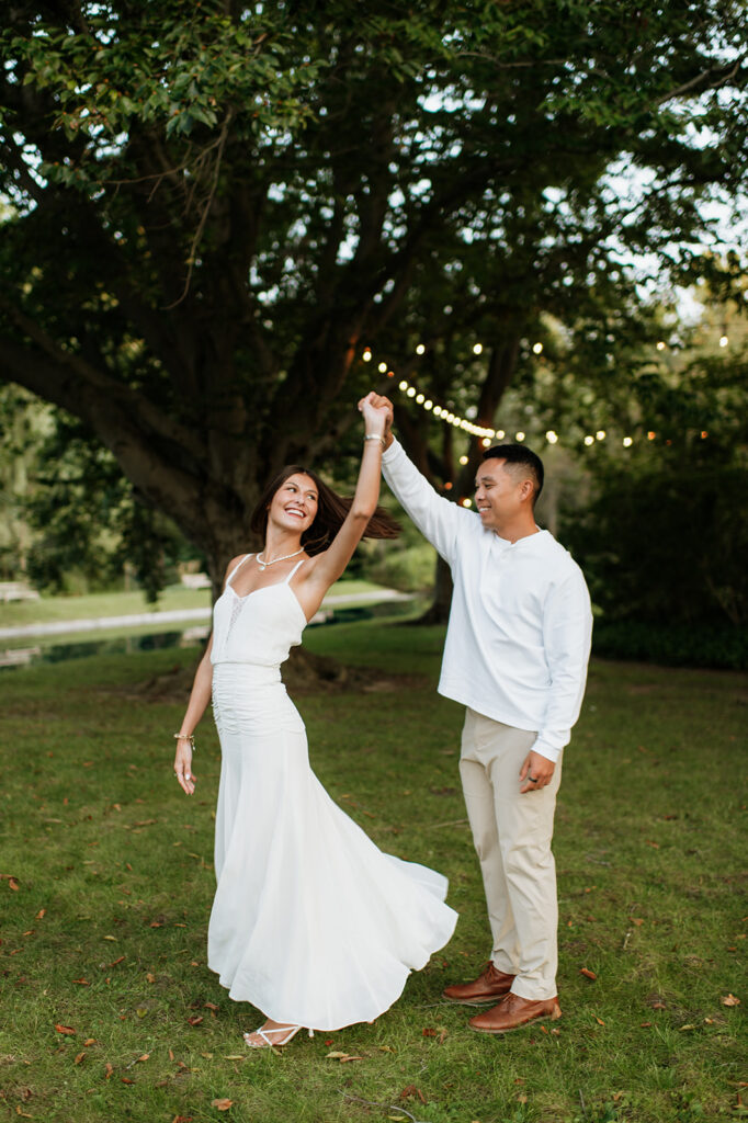 Couple twirling together on the lawn during golden hour Saint Mary’s College engagement photos.