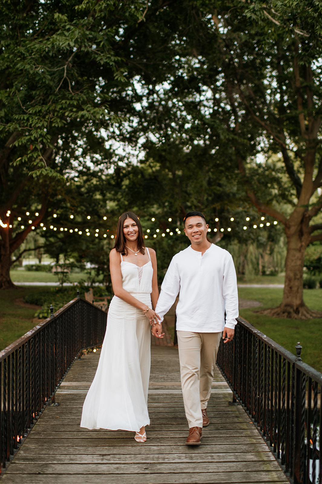 Couple holding hands while walking over the wooden bridge toward the island at Saint Mary’s College.