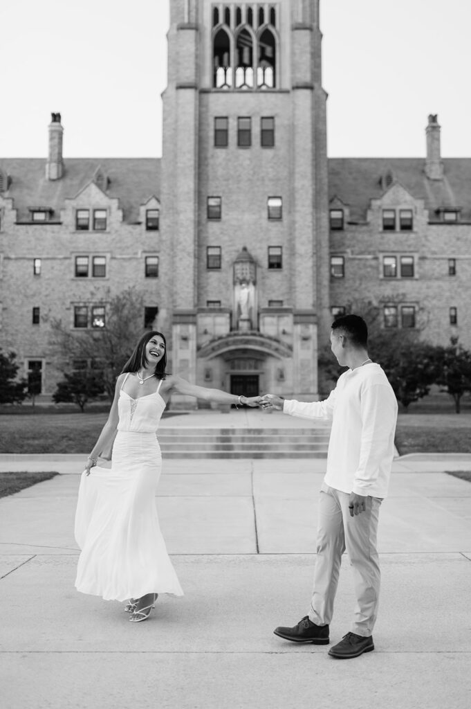 Black and white photo of couple dancing in front of the historic LeMans Hall building during Saint Mary’s College engagement photos.