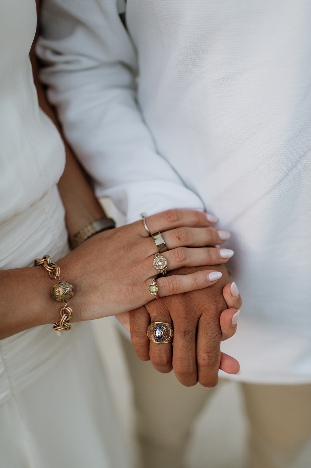 Close-up of engagement ring and jewelry on her hand resting gently on his arm.