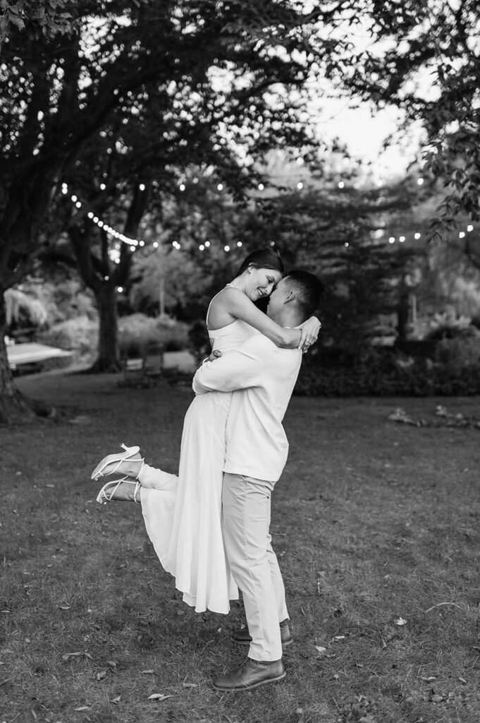 Romantic black and white photo of couple laughing as he lifts her during their Saint Mary’s College session.