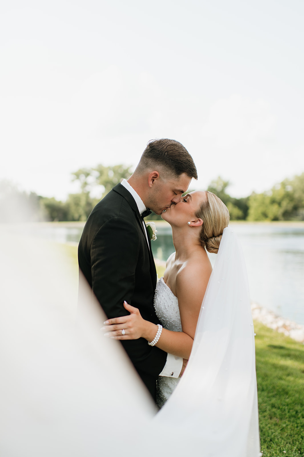 Bride and groom sharing a kiss with veil in the foreground at The Clubhouse venue.