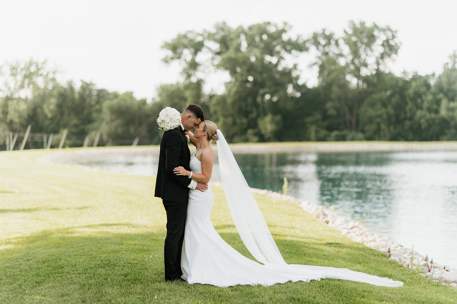 Bride and groom standing close together by the pond at The Clubhouse venue during newlywed portraits.