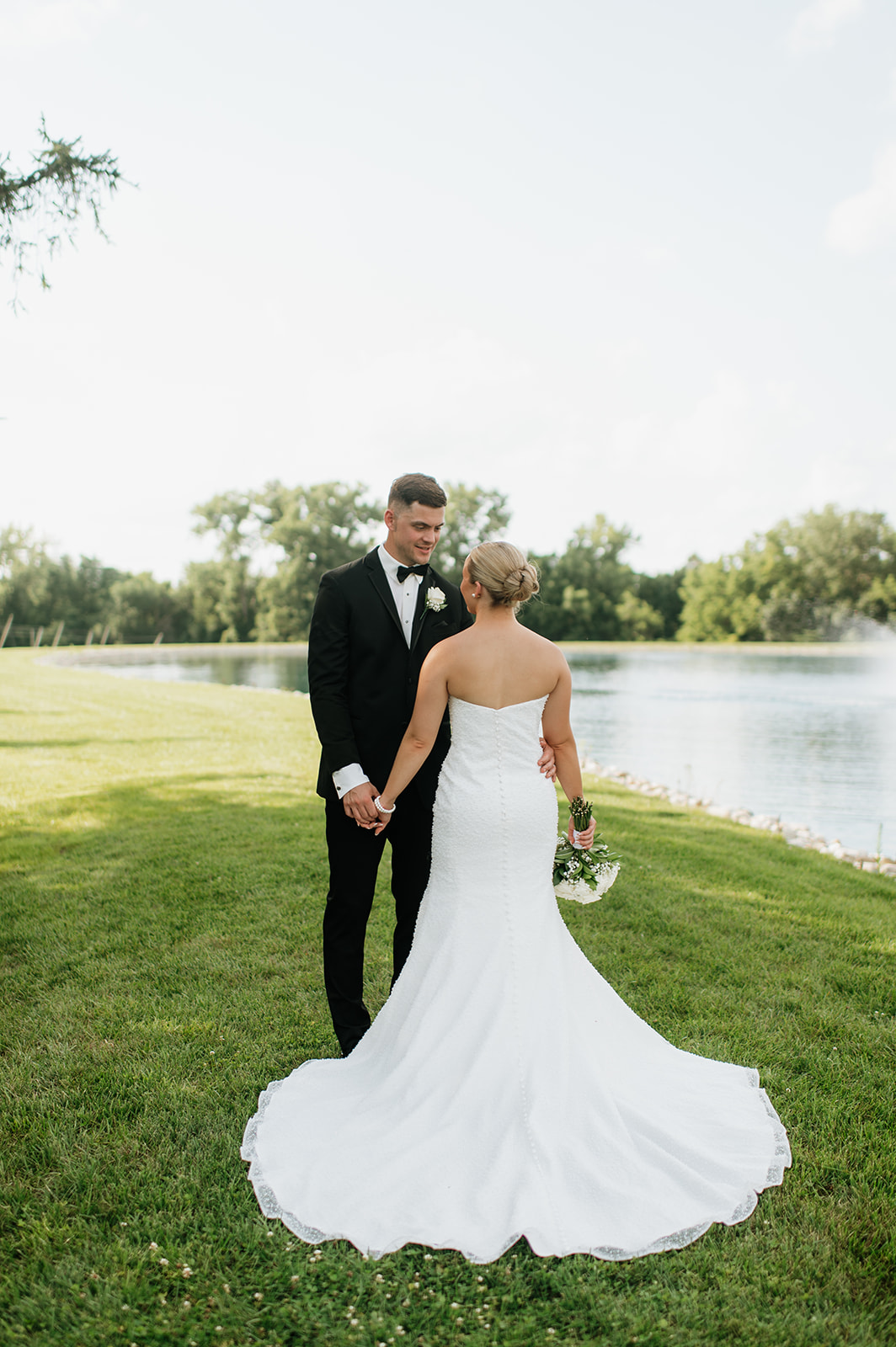 Bride posing with her back to the camera as she looks at the groom.