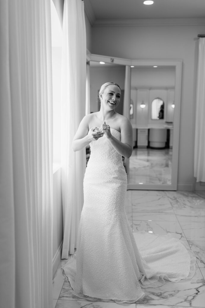 Bride smiling while getting ready in the bright bridal suite at The Clubhouse Venue.
