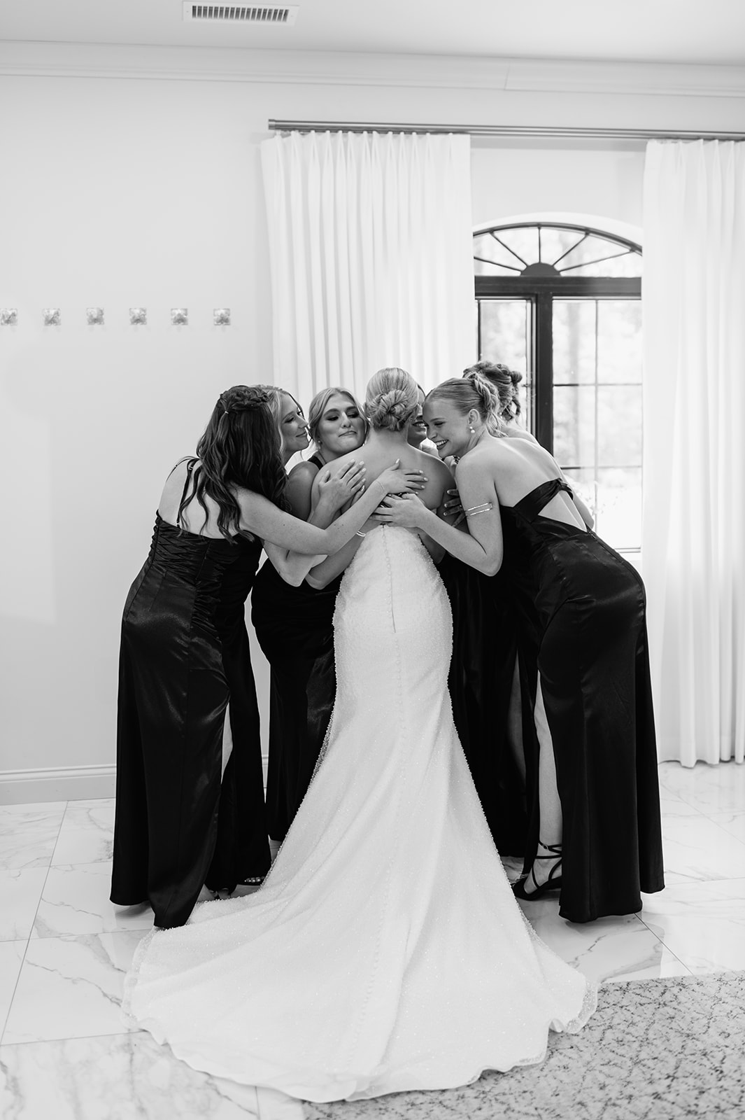 Bride hugging bridesmaids during a first look inside the bridal suite at The Clubhouse Venue.