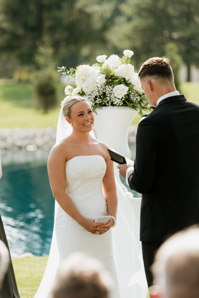 Close up shot of the bride smiling as the groom reads his vows to her at The Clubhouse Venue in Huntington, Indiana