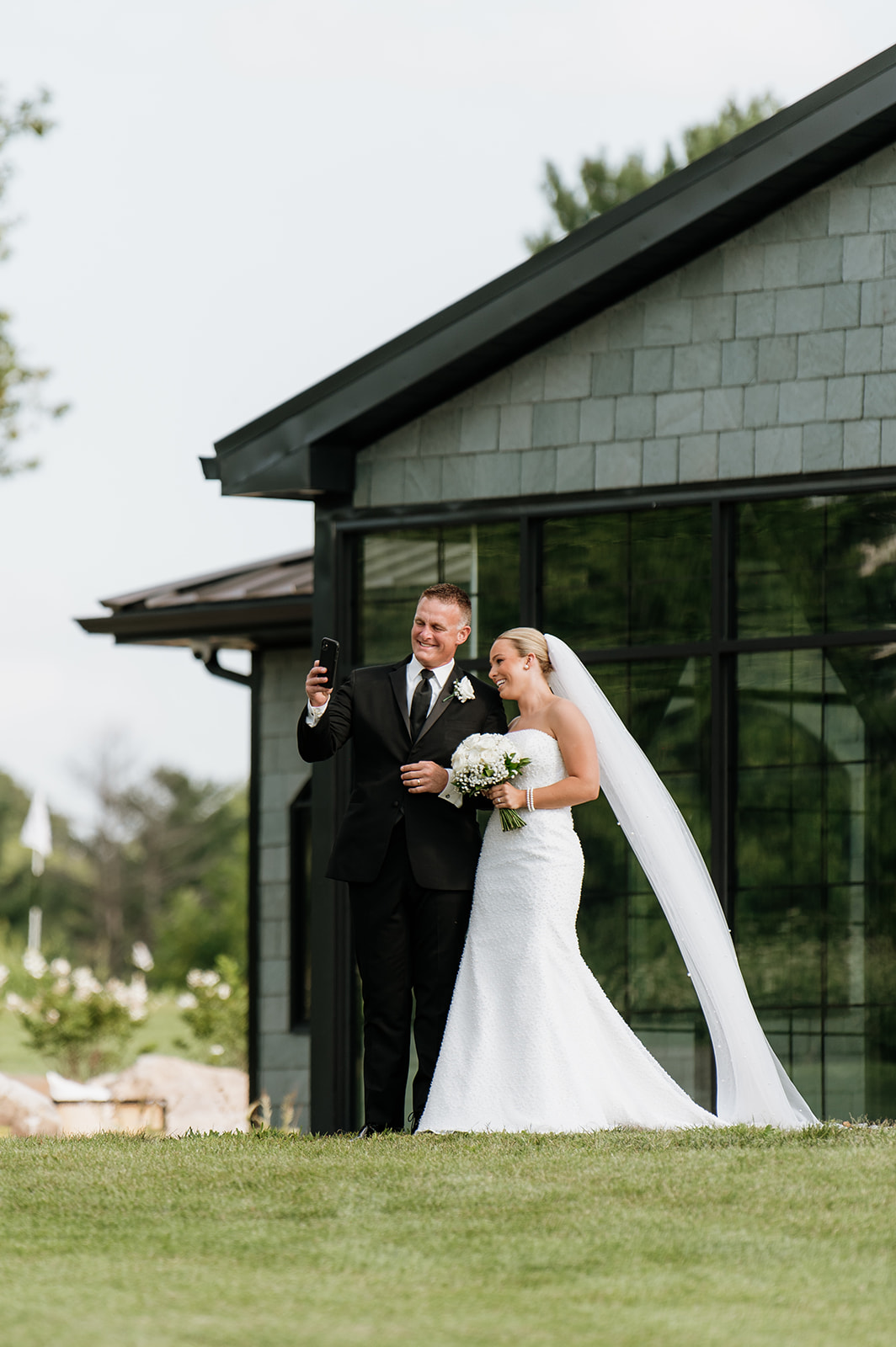 Bride and her father taking a selfie before walking down the aisle at The Clubhouse Venue.