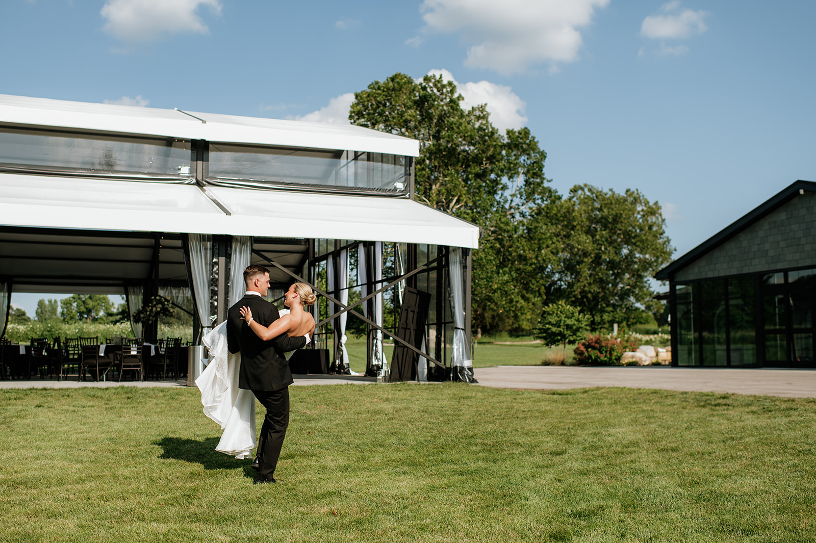 Groom carrying the bride after the ceremony on the grounds of The Clubhouse Venue.
