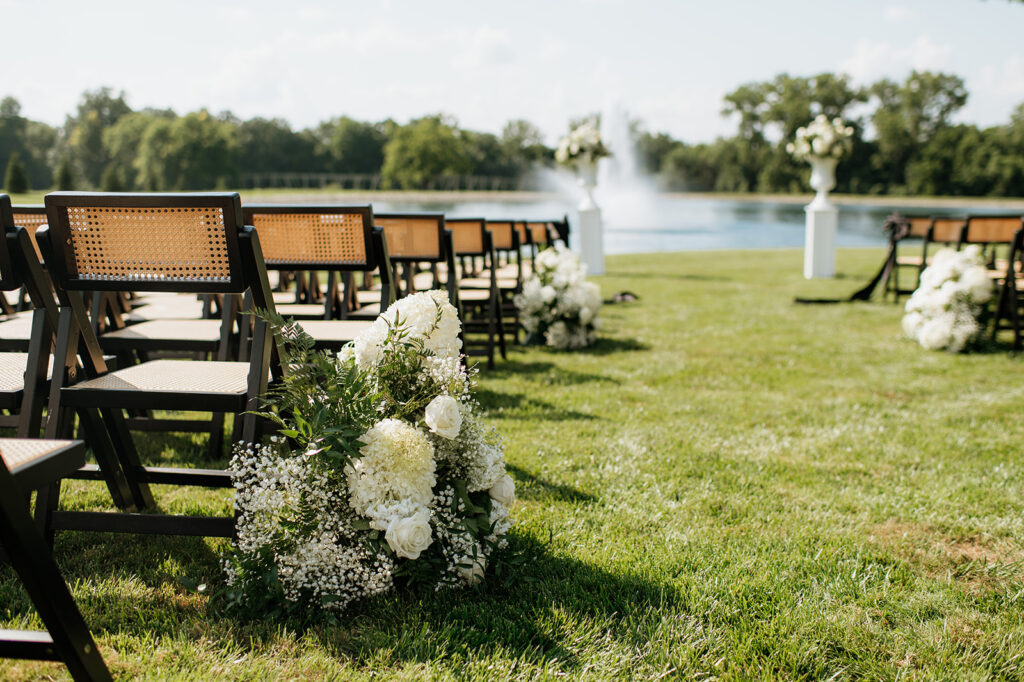 Close-up of aisle florals and ceremony chairs beside the pond at The Clubhouse Venue.