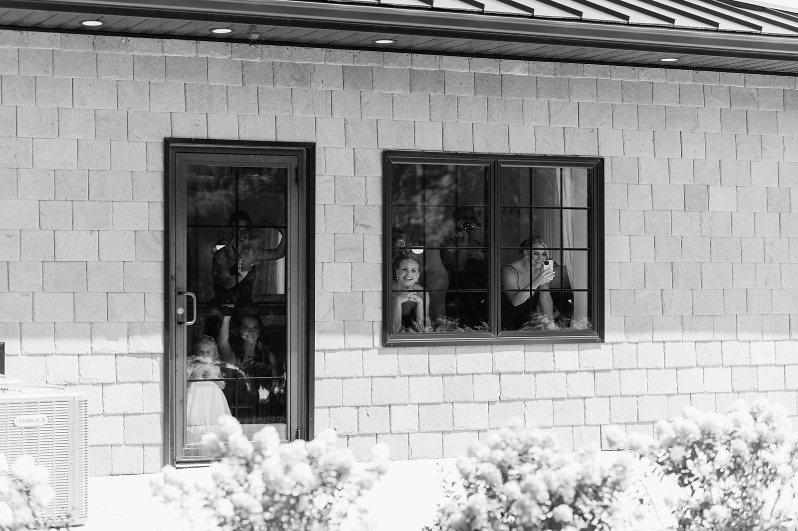 Bridesmaids watching out the window as the bride shares a first look with her father