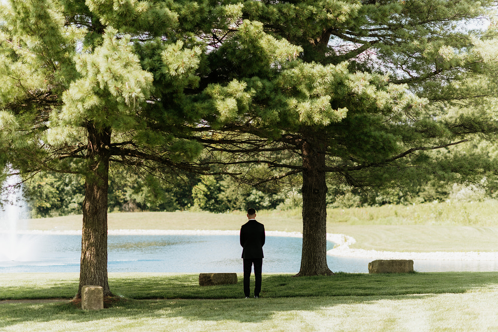 Bride facing the pond before sharing a first look with his bride