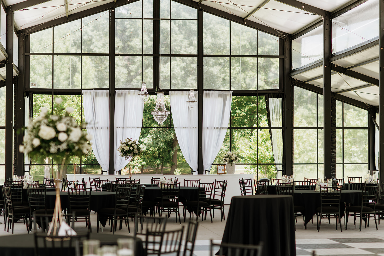 Wide view of The Clubhouse Venue reception space with floor-to-ceiling windows and chandeliers.