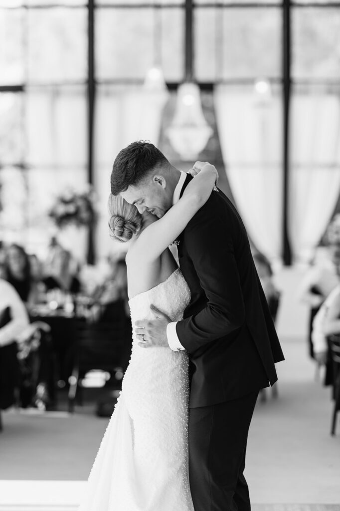 Black and white photo of the bride and groom dancing closely during their first dance
