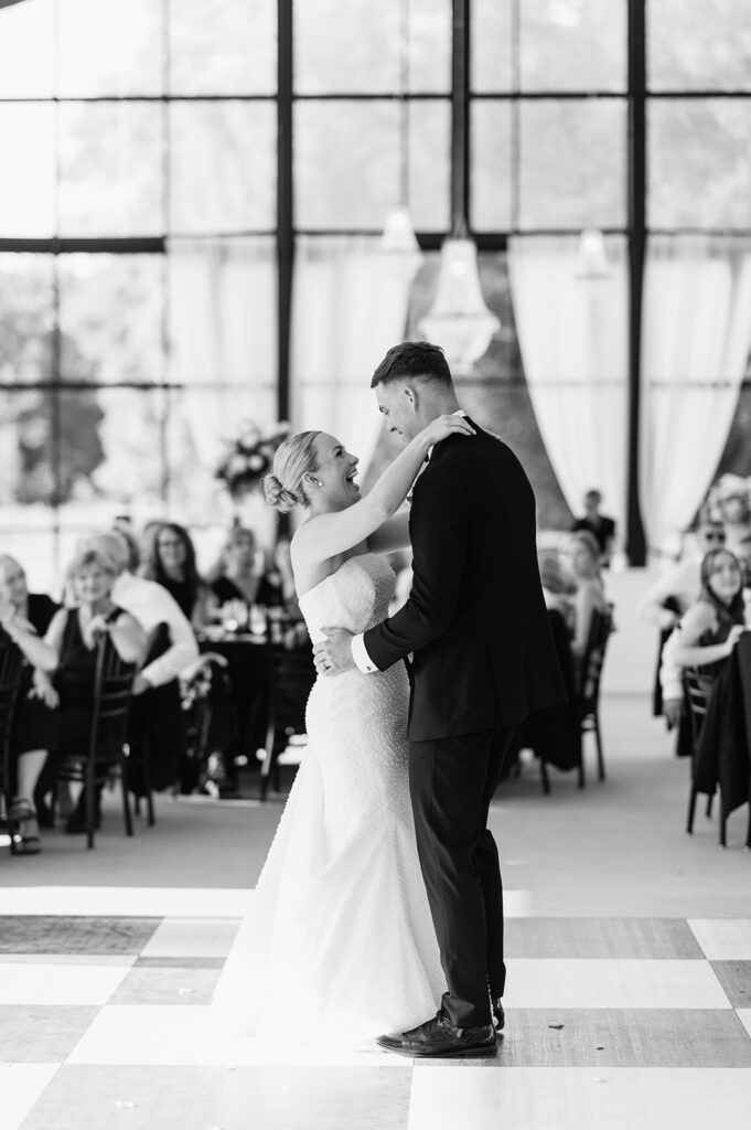 Black and white photo of the bride and groom laughing during their first dance at The Clubhouse Venue in Huntington, Indiana