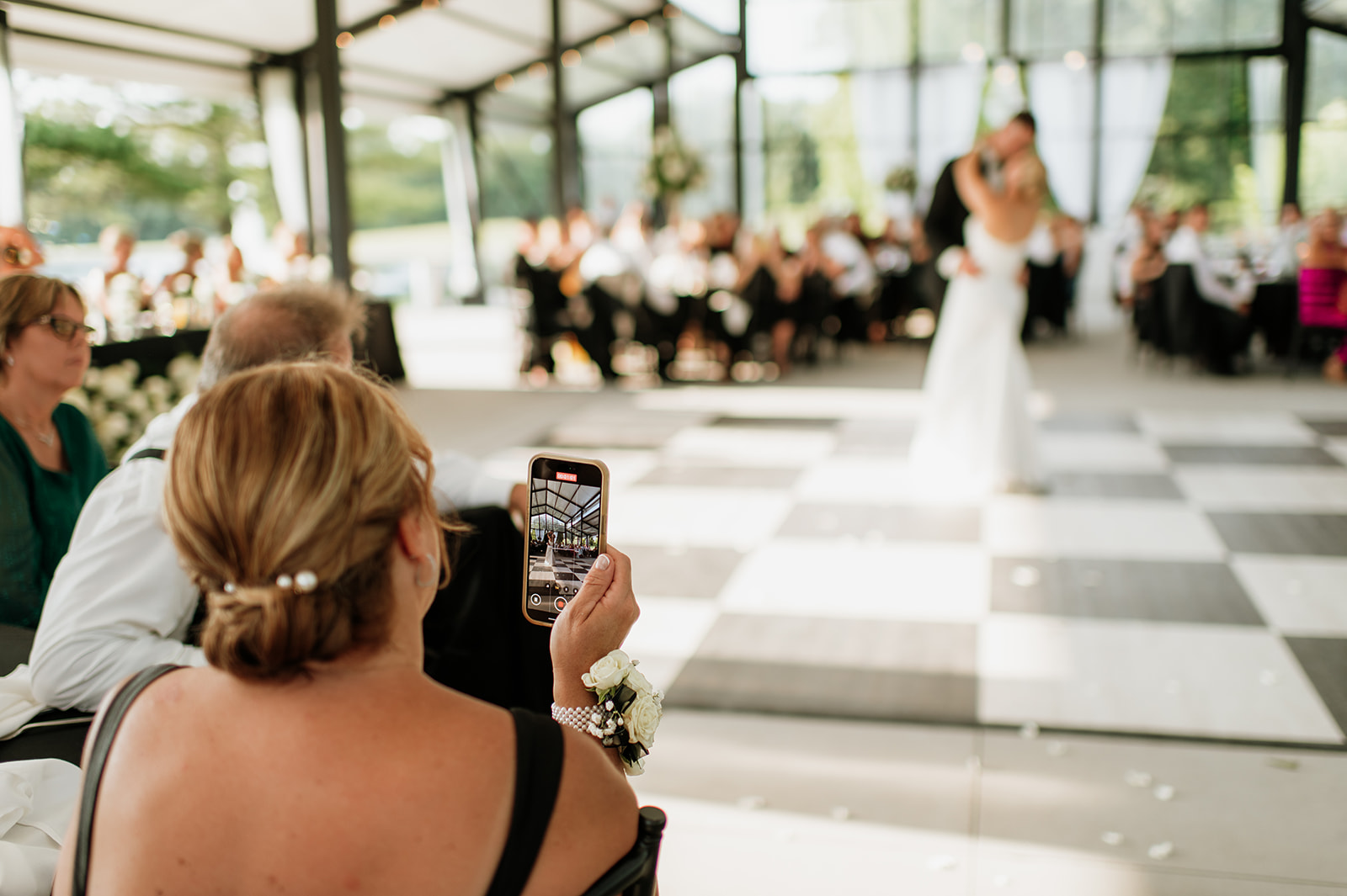 Guest recording a video of the bride and groom sharing a first dance