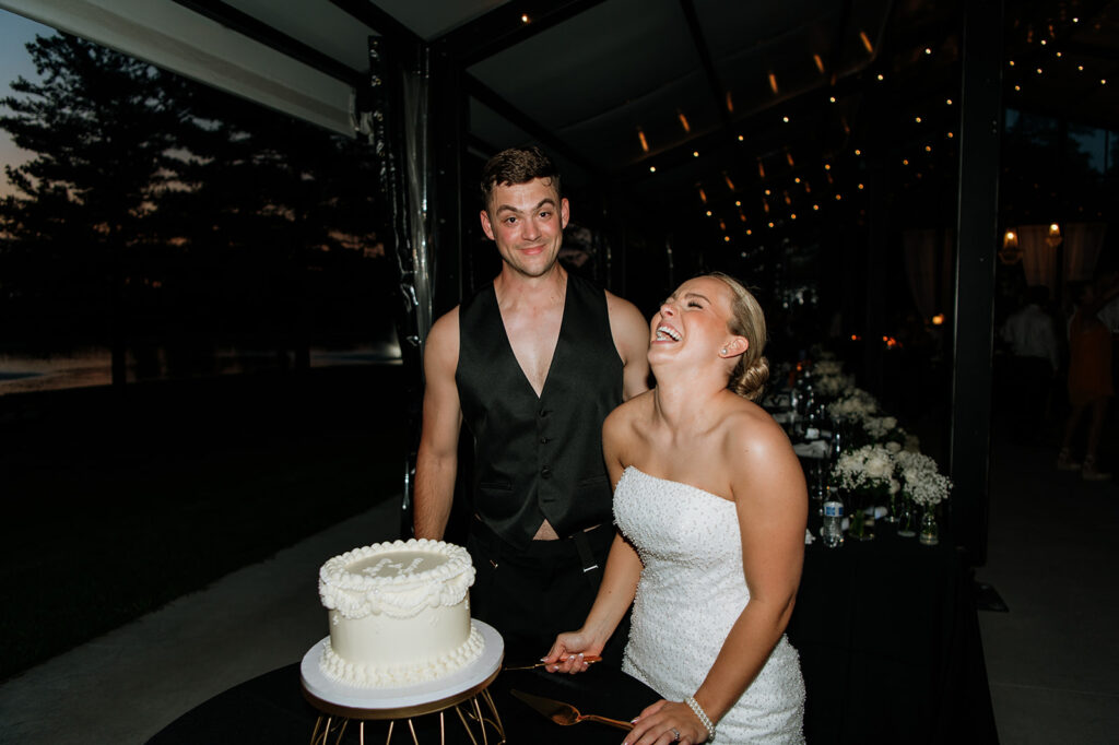 Bride and groom laughing while cutting their wedding cake at The Clubhouse Venue.