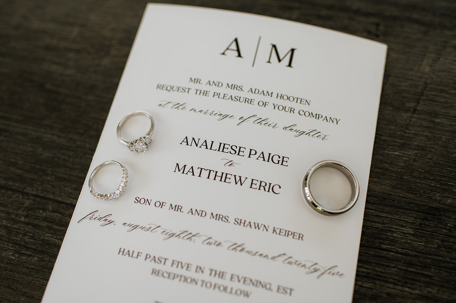Close up wedding detail shot of the wedding invitation with brides rings and grooms band