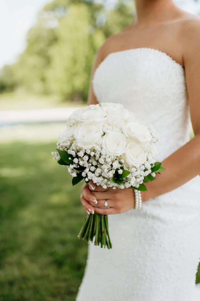 Close up shot of a bride standing with her bouquet in front of the pond at The Clubhouse Venue.