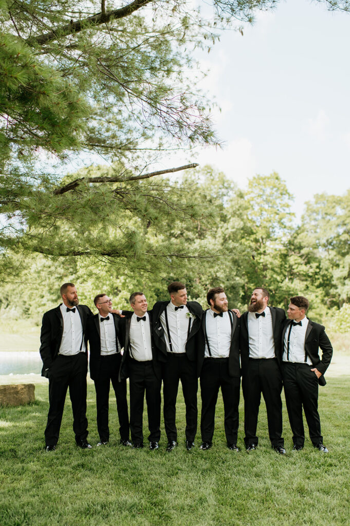 Groomsmen standing together laughing on the lawn at The Clubhouse Venue.