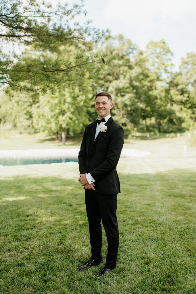 Groom standing for a portrait in front of the pond at The Clubhouse Venue.