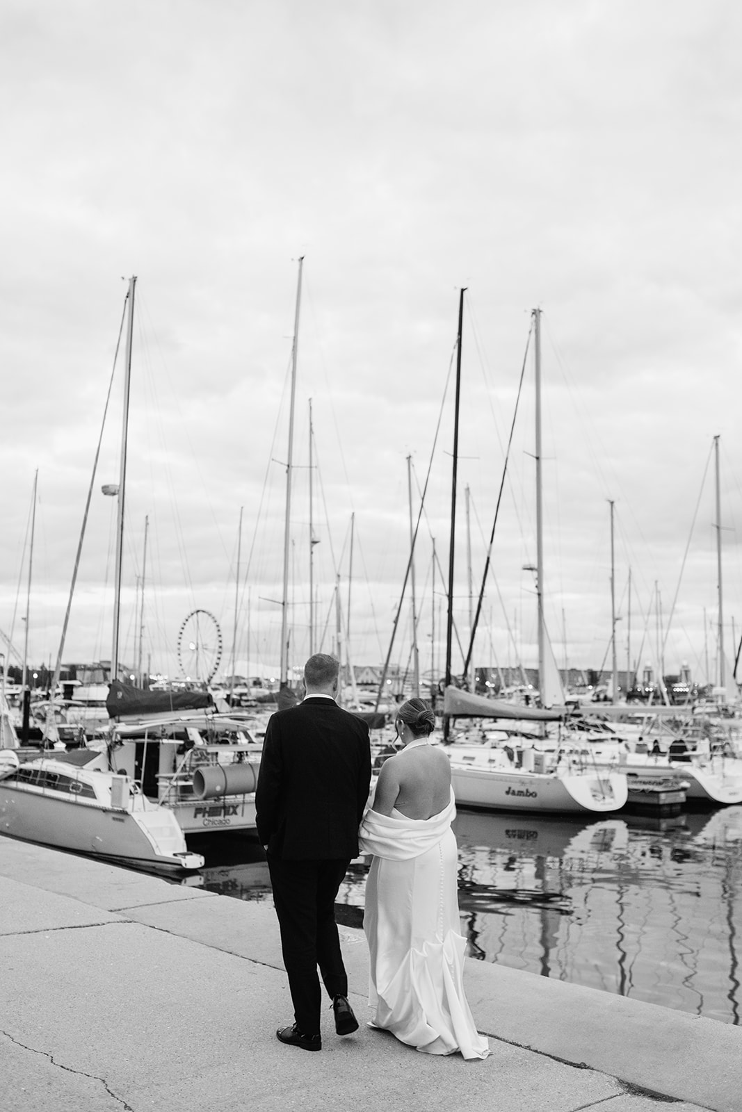 Bride walking along the dock with sailboats during a Chicago yacht wedding portrait session.