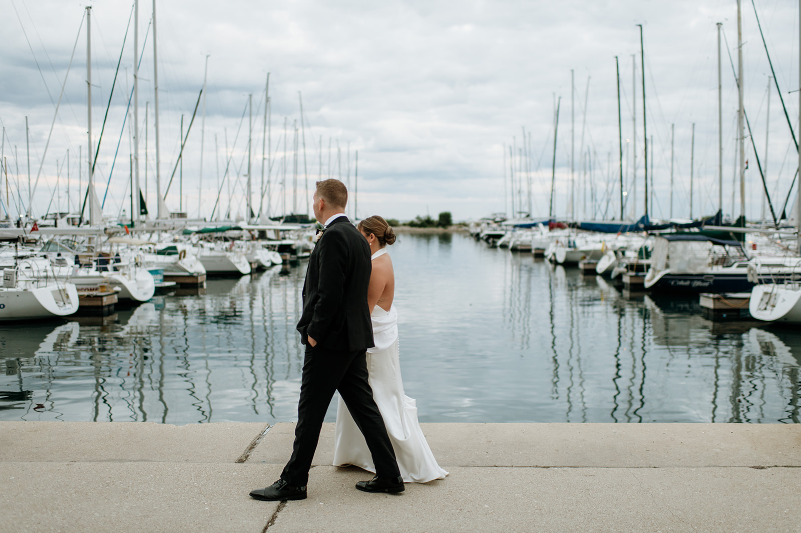 Bride and groom walking hand in hand along the marina during their Chicago yacht wedding portraits.