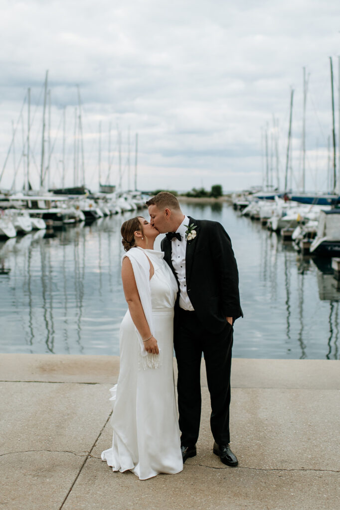 Bride and groom kissing on the dock during their Chicago yacht wedding portraits.