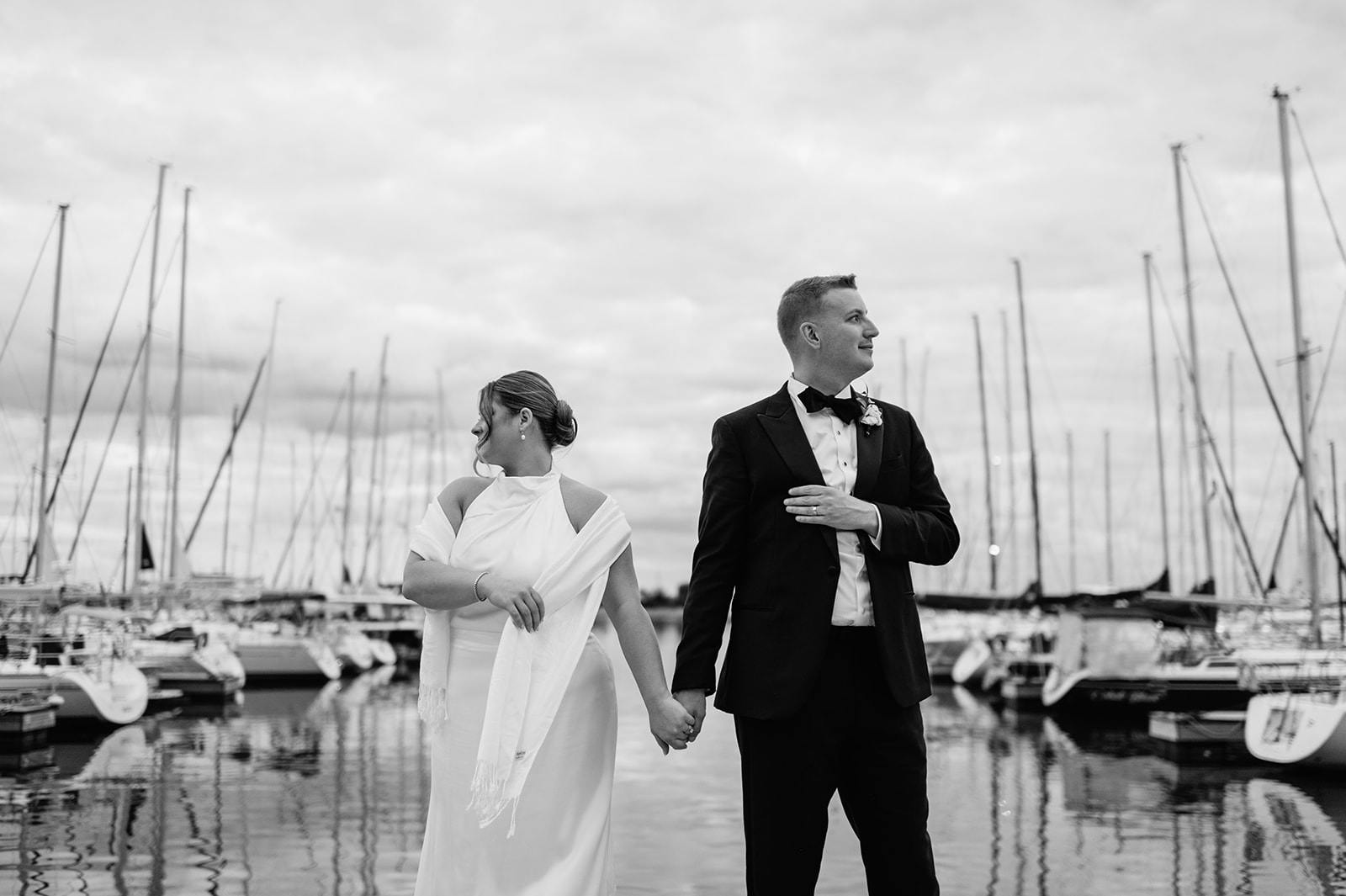 Editorial black and white wedding portraits of a couple holding hands on the dock for their Chicago yacht wedding after-party.