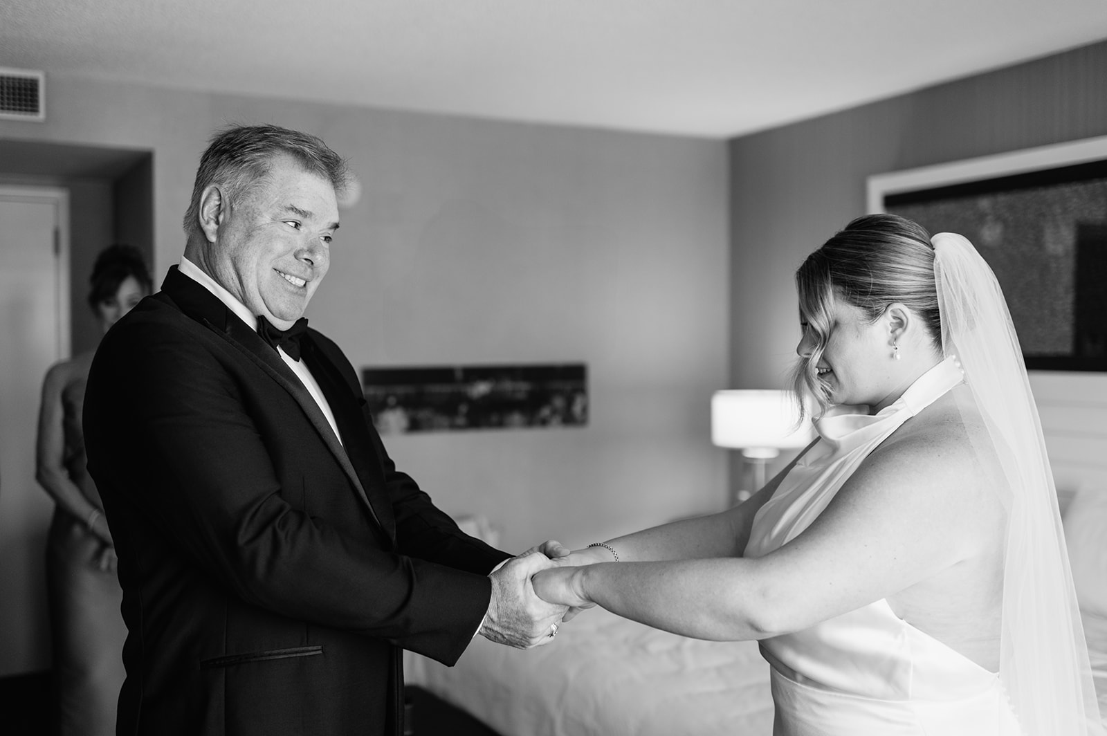 Emotional first look between the bride and her father in a hotel room.