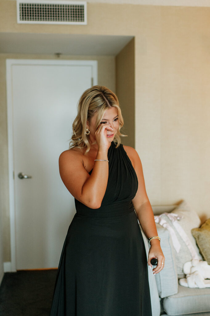 Bridesmaid wiping away tears as she watches the bride get ready.
