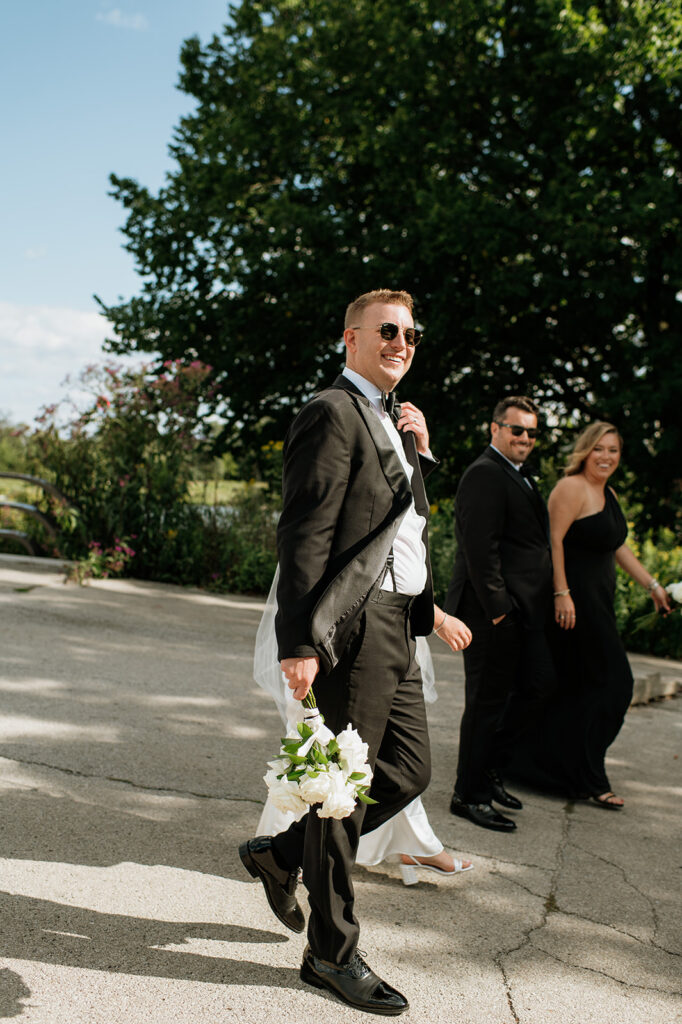 Groom adjusting his jacket while walking with the wedding party in Lincoln Park.