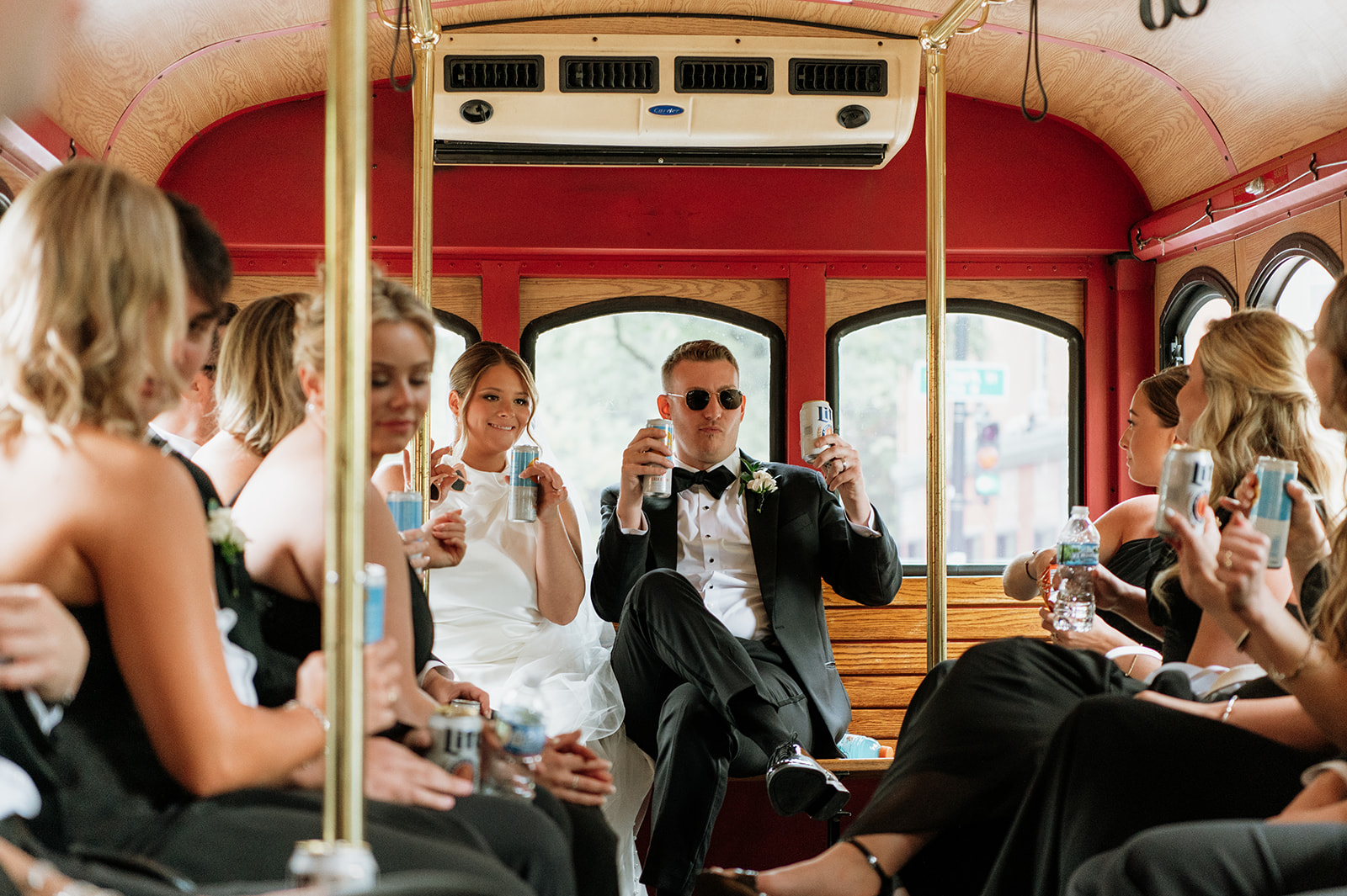Bride and groom celebrating with drinks and their wedding party on a trolley in Chicago.