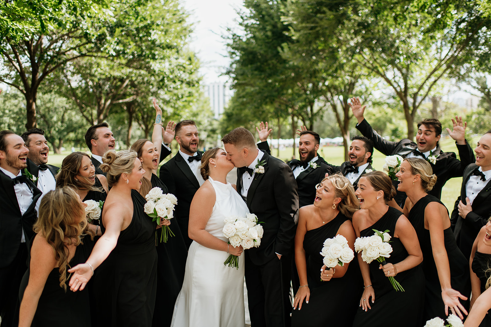 Bride and groom kissing as the wedding party cheers during Chicago wedding portraits.