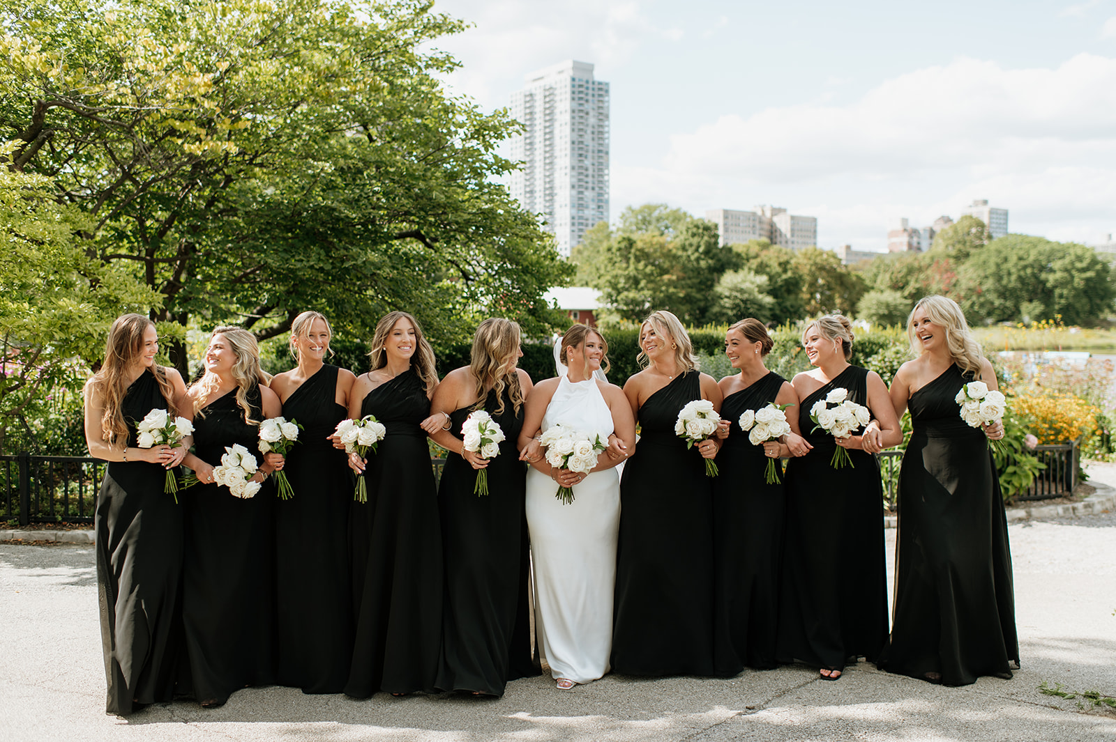 Bridesmaids in black dresses standing together during Lincoln Park wedding photos.