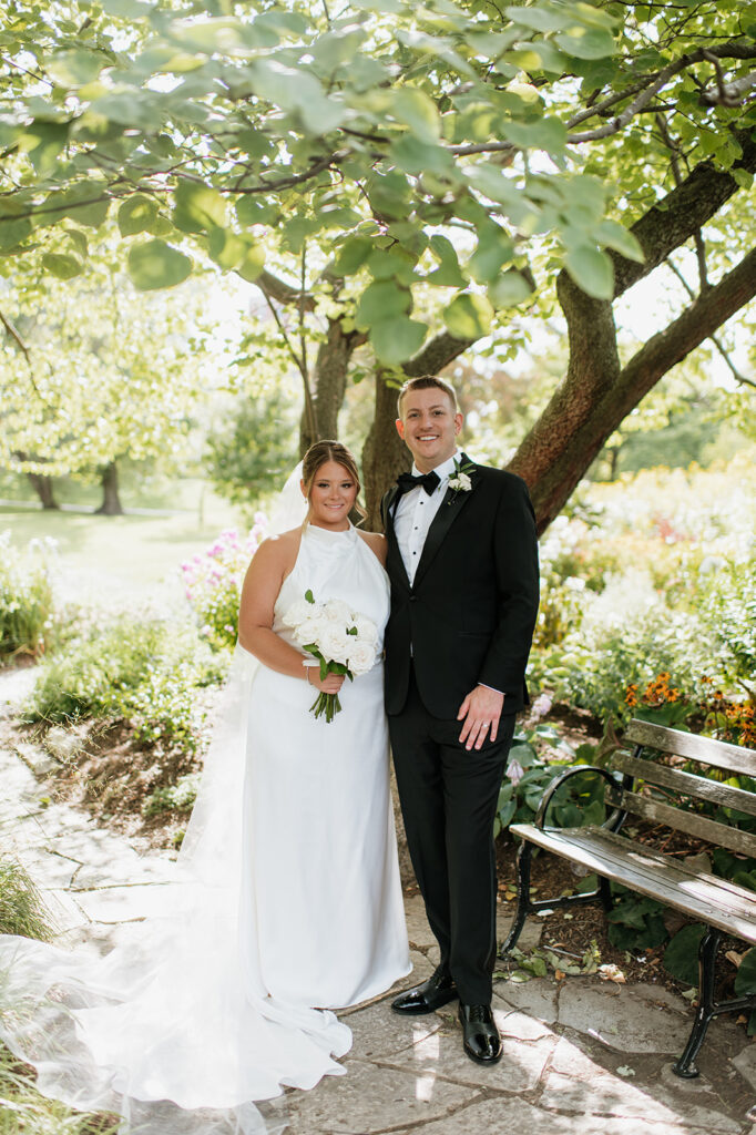 Bride and groom standing together beneath trees during Chicago wedding portraits.