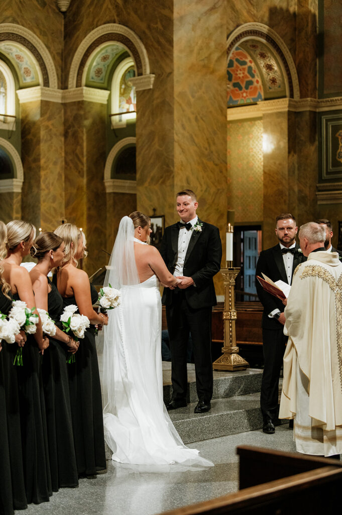 Bride and groom holding hands during their Saint Clement Parish wedding ceremony in Chicago.