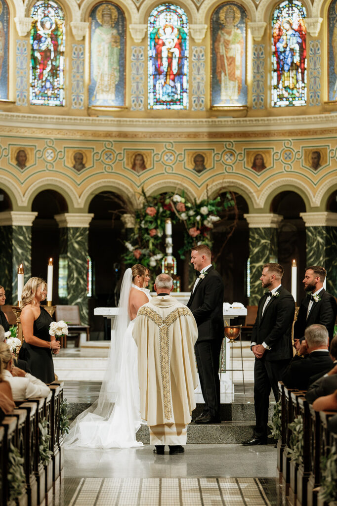 Bride and groom holding hands at the altar during their Saint Clement Parish wedding ceremony in Chicago.